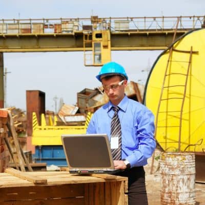 Field site plan review - ALTA SURVEY Fortworth Civil engineer reviewing infrastructure plans on site using a laptop