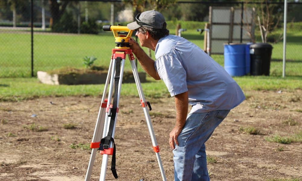 Property boundary survey field work - ALTA SURVEY Fortworth A licensed land surveyor measuring a property line using field equipment