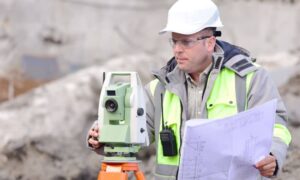 Licensed land surveyor reviewing site plans while performing an ALTA survey to verify property details before a real estate transaction