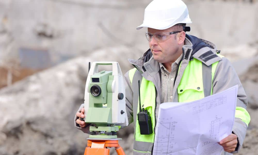 Land surveyor checking property plans on site - ALTA SURVEY Fortworth Licensed land surveyor reviewing site plans while performing an ALTA survey to verify property details before a real estate transaction