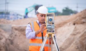 Commercial property surveyor measuring land with a total station before construction begins